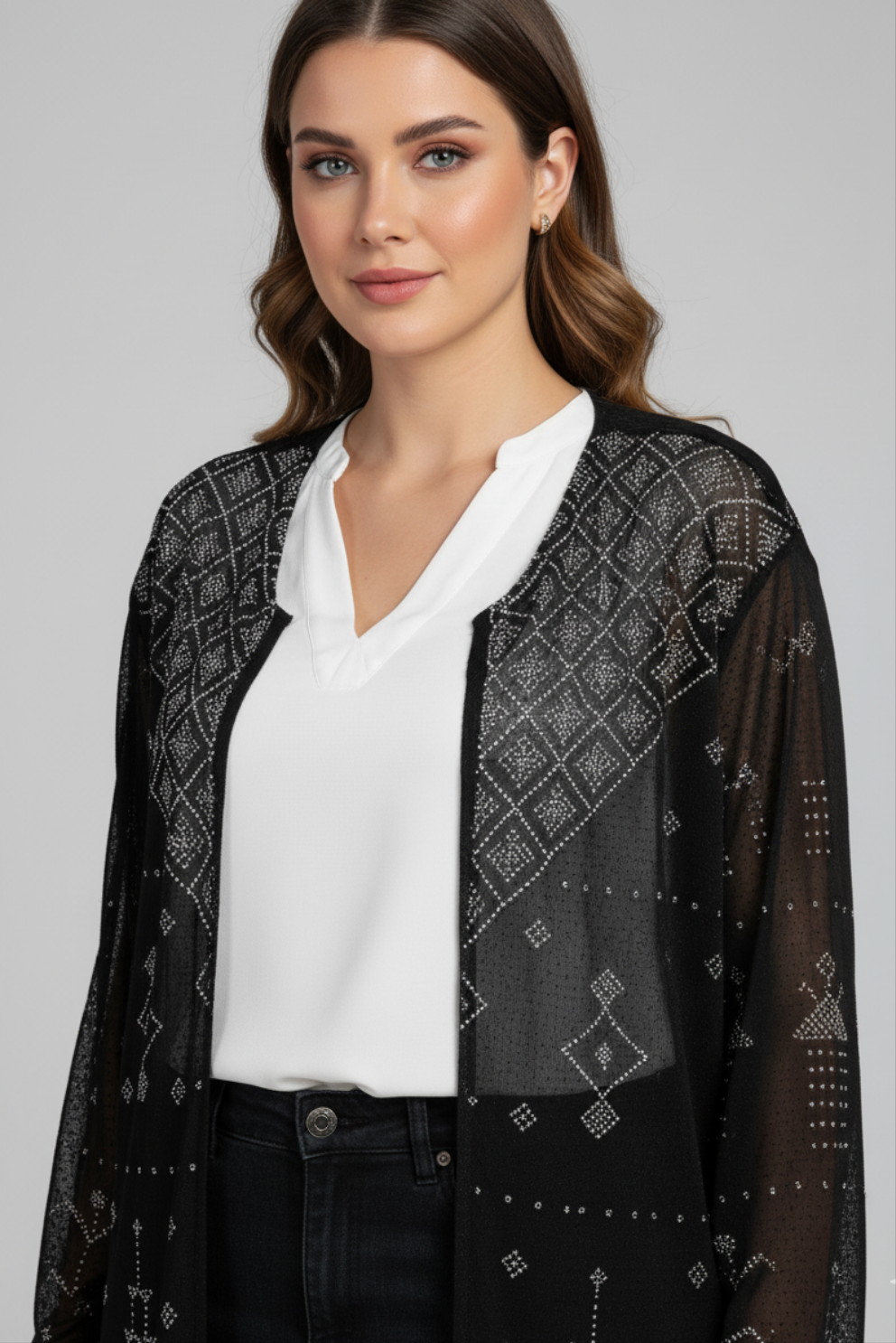 Woman wearing a black lace Tally tunic over a white blouse and black jeans on gray background