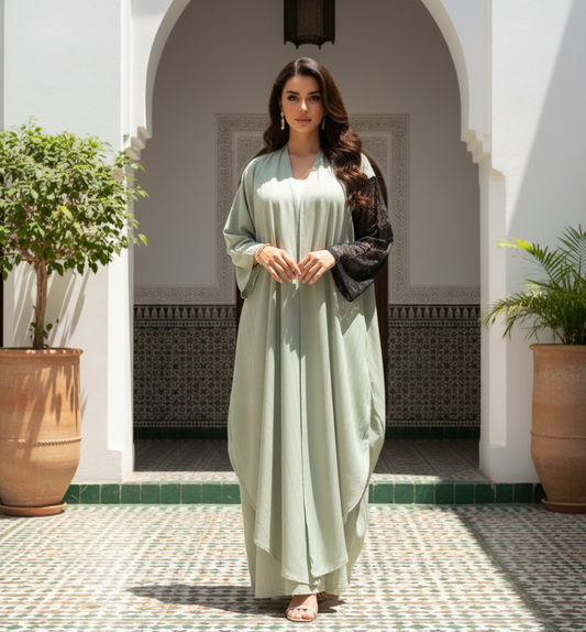 Woman in a light green dress standing in a sunlit courtyard with plants and arches.
