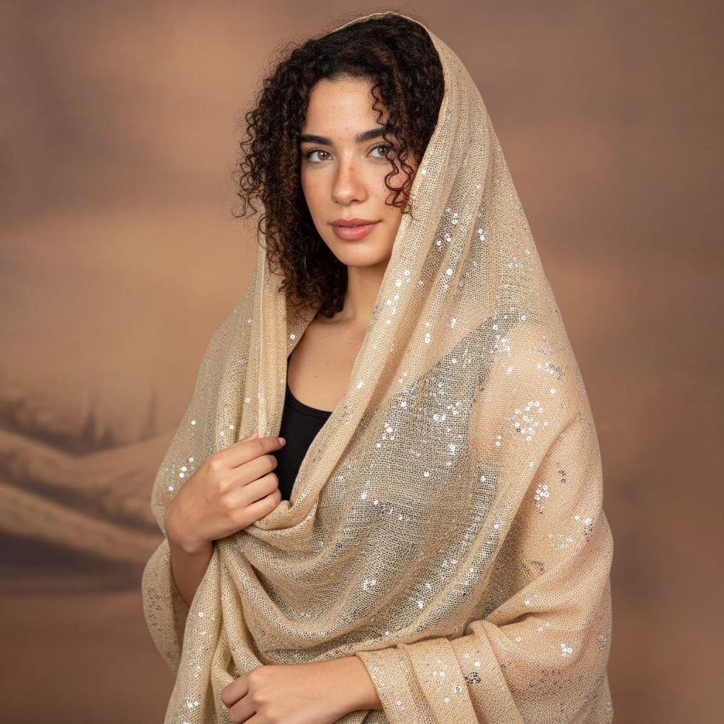 Woman wearing a beige sequined shawl against a brown background