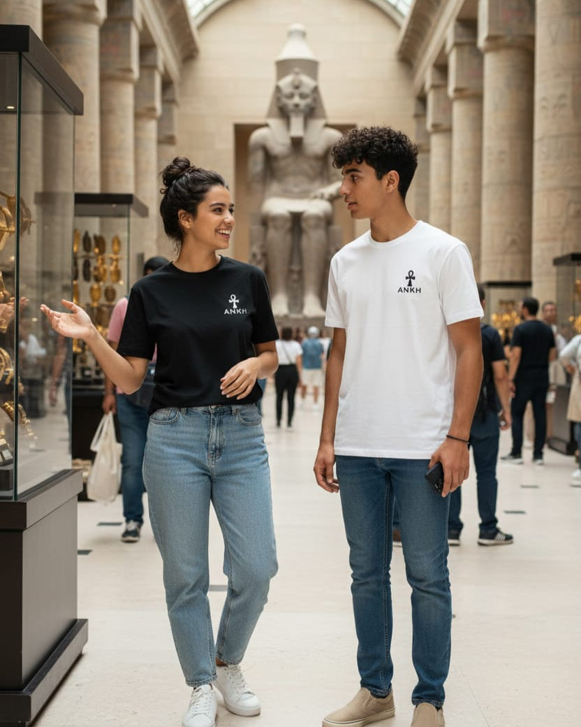Two people walking through a museum with classical architecture and statues in the background.