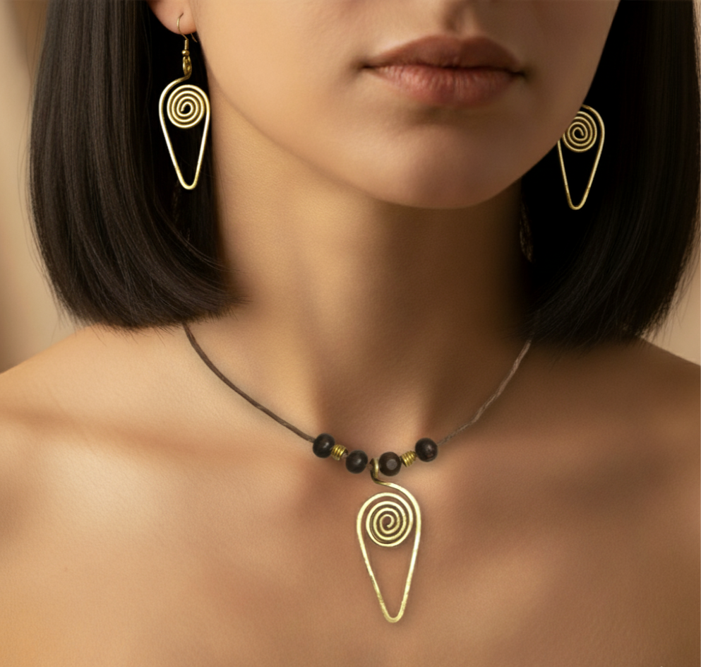 Close-up of a woman wearing gold spiral earrings and a matching necklace against a neutral background.