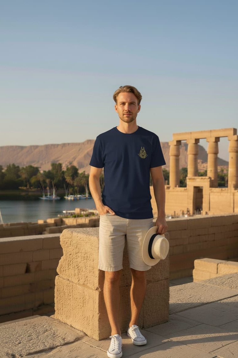 Man standing in front of ancient ruins with a body of water and mountains in the background