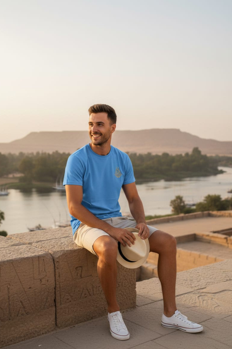Man sitting on a stone ledge by a scenic lakeside with mountains in the background