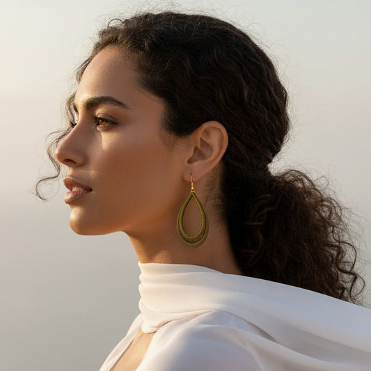 Woman wearing gold earrings with a plain background