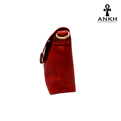 A genuine leather cross bag in red color with handcrafted brass accessories and multiple pockets, displayed on a white mannequin bust with a black logo of ANKH - The Egyptian Royalty.