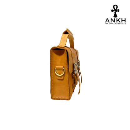 A genuine leather cross bag with handcrafted brass accessories and multiple pockets, displayed on a white background with a black logo of ANKH - The Egyptian Royalty.