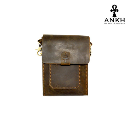 A genuine leather cross bag in navy blue and tan color with handcrafted brass accessories and multiple pockets, displayed on a white mannequin bust with a black logo of ANKH - The Egyptian Royalty.