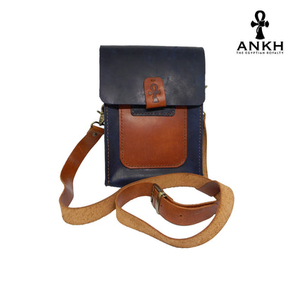 A genuine leather cross bag in navy blue and tan color with handcrafted brass accessories and multiple pockets, displayed on a white mannequin bust with a black logo of ANKH - The Egyptian Royalty.