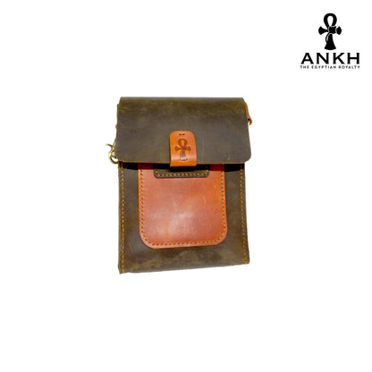 A genuine leather cross bag in navy blue and tan color with handcrafted brass accessories and multiple pockets, displayed on a white mannequin bust with a black logo of ANKH - The Egyptian Royalty.