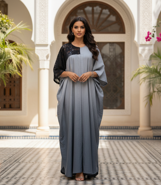 Woman in a long, light blue dress with black lace sleeves standing in a decorative courtyard.
