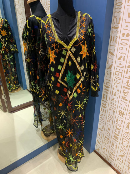 A traditional Egyptian tally gown with hand embroidery, displayed on a mannequin, featuring geometric and floral patterns with a black base.