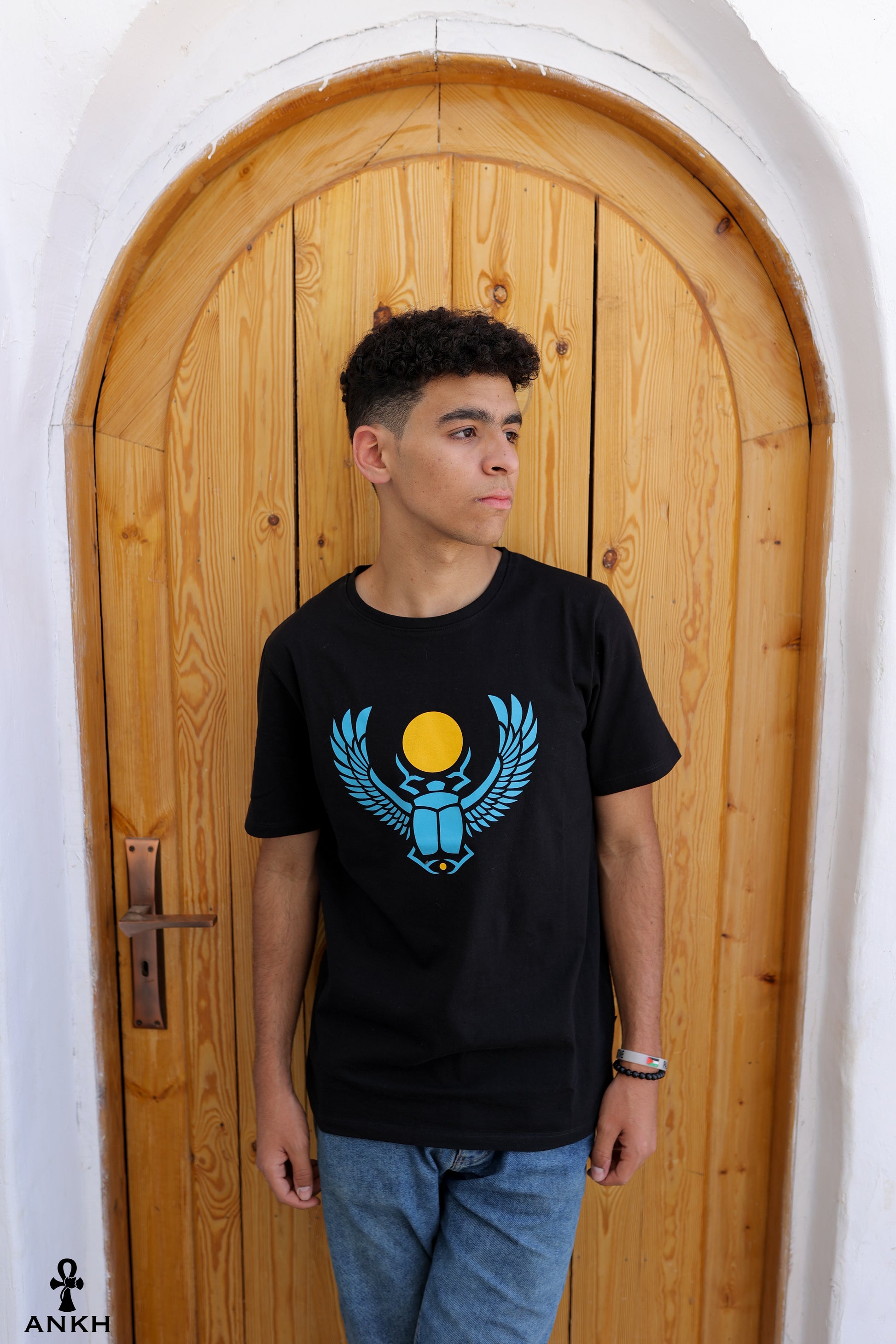 A man wearing a t-shirt with a printed Ancient Egyptian scarab symbol, made from soft 100% Egyptian cotton