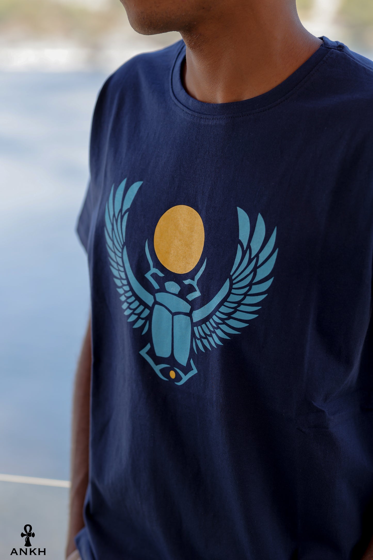 A man wearing a t-shirt with a printed Ancient Egyptian scarab symbol, made from soft 100% Egyptian cotton