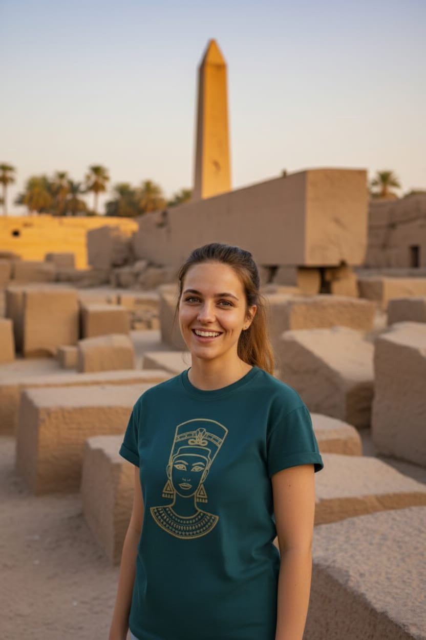 Woman wearing a teal t-shirt with a Nefertiti design in front of ancient ruins.
