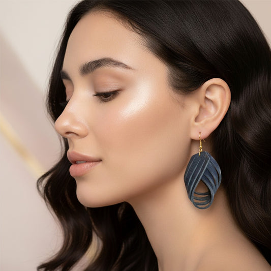 Woman wearing blue leaf-shaped earrings with a neutral background