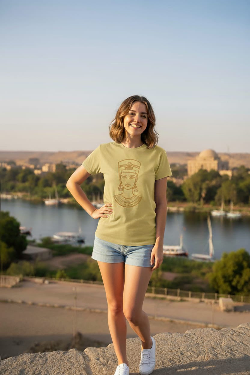 Woman wearing a yellow t-shirt with a design, standing outdoors with a scenic background.