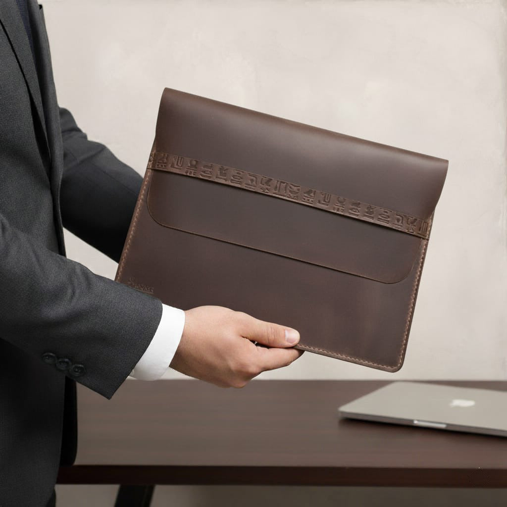Person holding a brown leather envelope with a blurred background