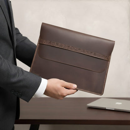 Person holding a brown leather envelope with a blurred background