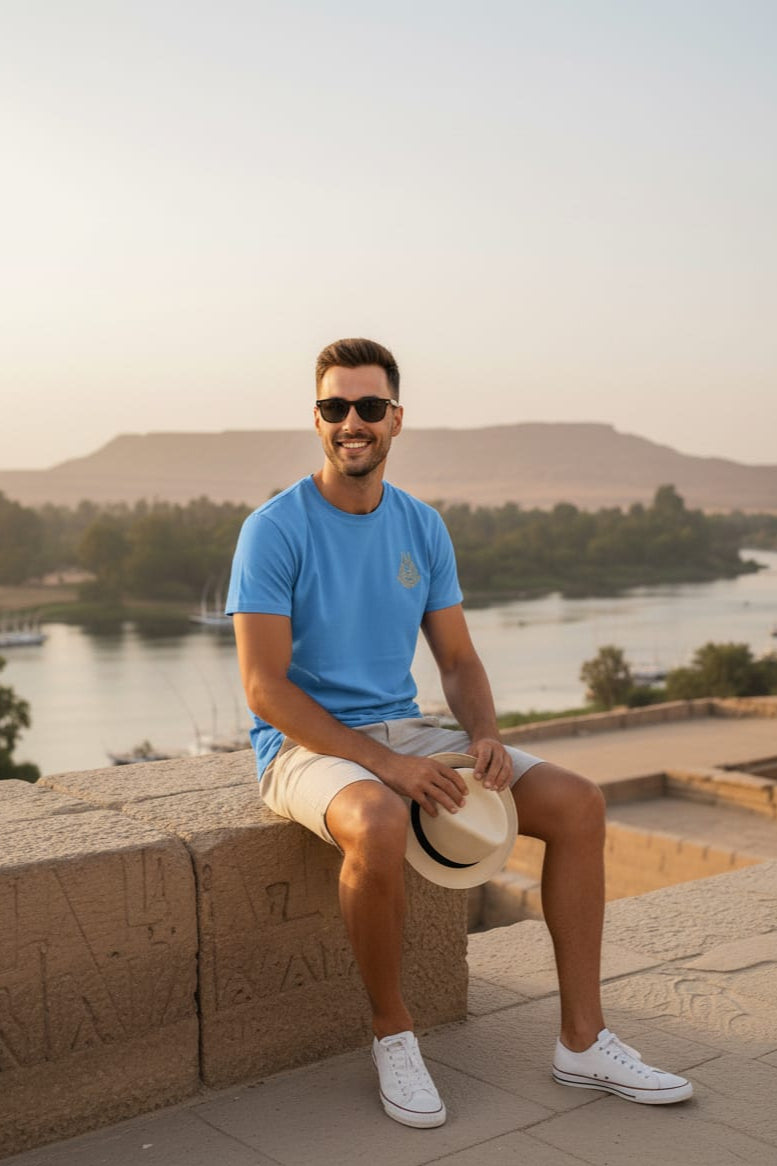 Man in a blue shirt sitting on stone steps with a scenic background