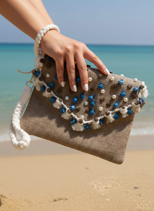 Hand holding a beaded clutch on a beach