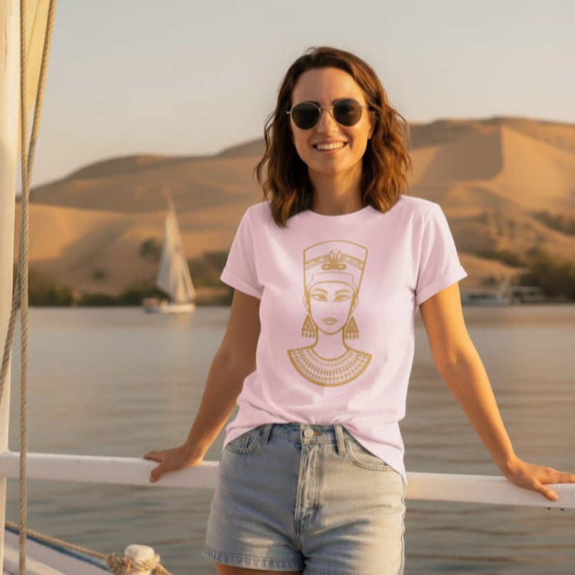 Woman wearing a pink t-shirt with a graphic design, standing on a boat with a scenic background.