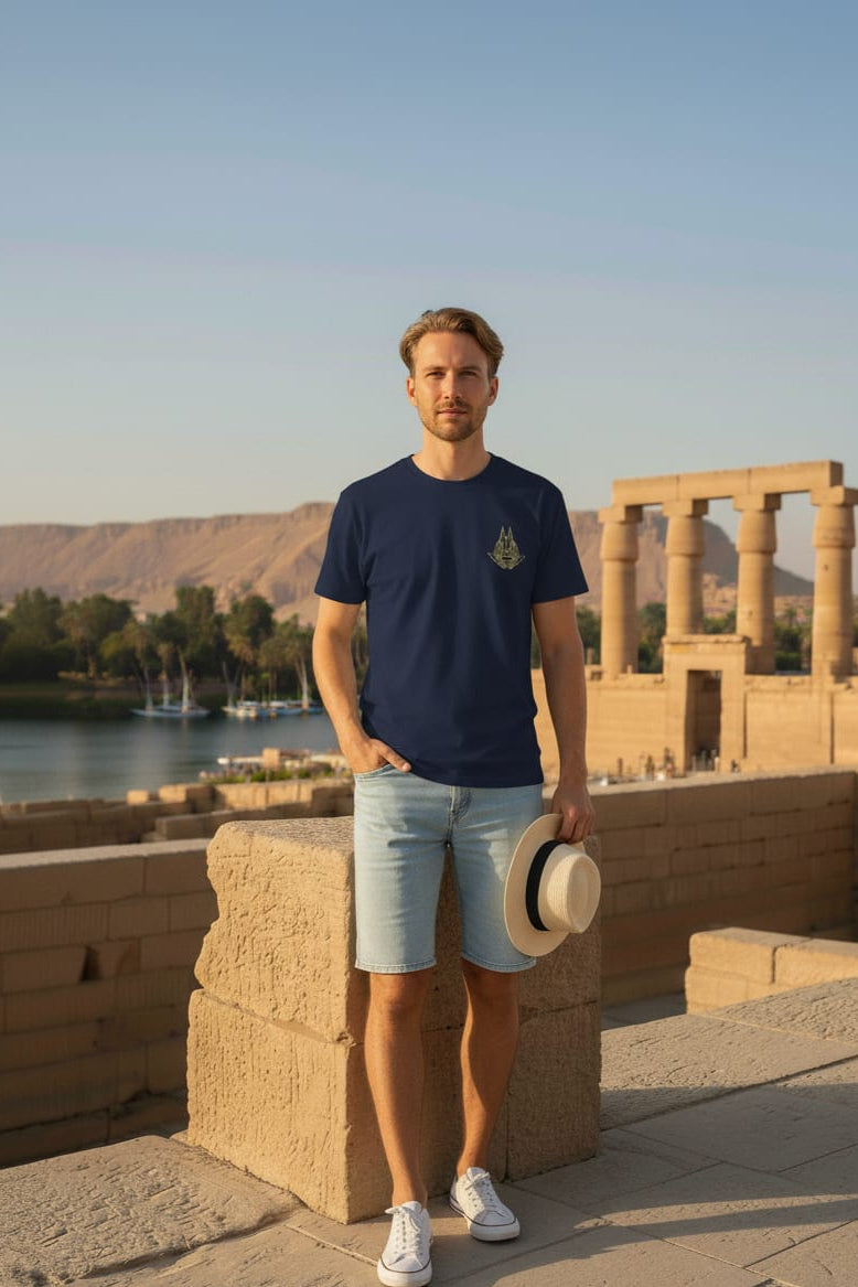 Man standing in front of ancient ruins with a body of water and mountains in the background