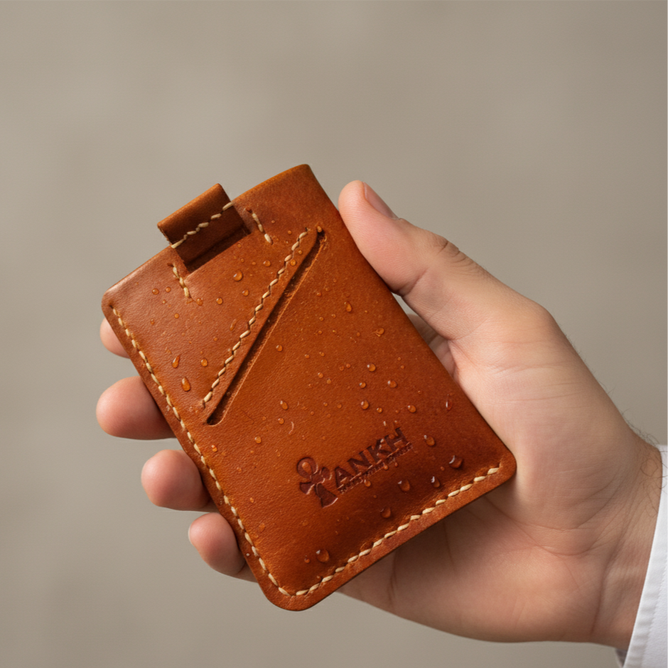 Hand holding a brown leather cardholder with 'YANKEE' branding against a beige background