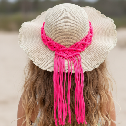 Beige straw hat with pink macrame accessory on a blurred beach background