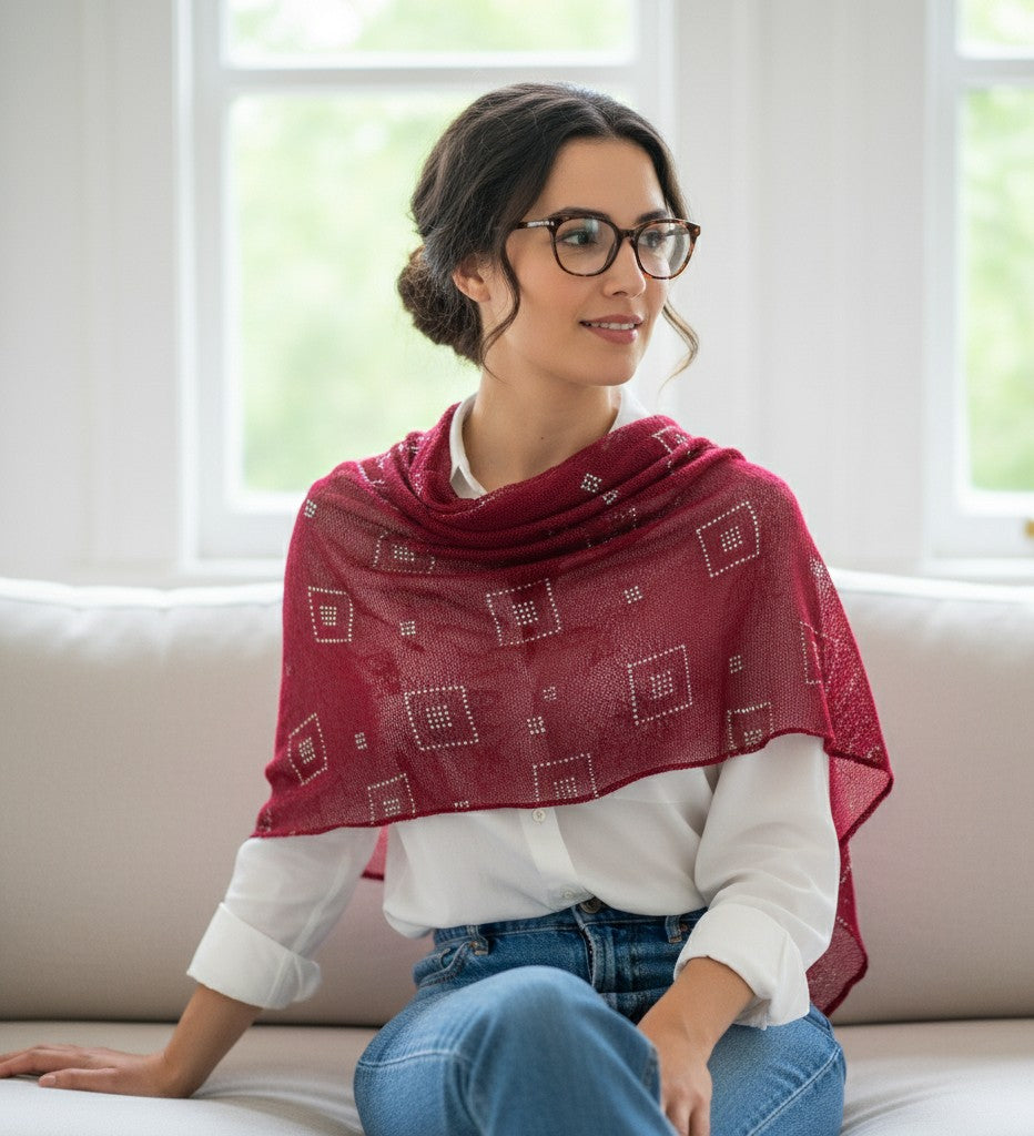 Woman wearing a red patterned shawl sitting on a couch.