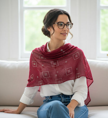 Woman wearing a red patterned shawl sitting on a couch.
