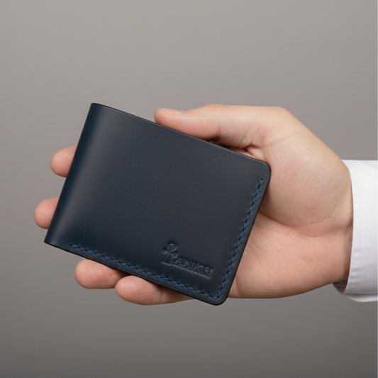 Hand holding a navy leather wallet against a gray background