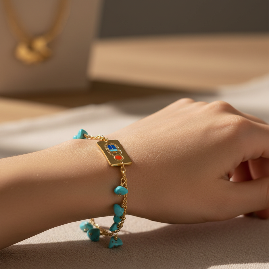 Gold bracelet with turquoise beads on a wrist, with a neutral background