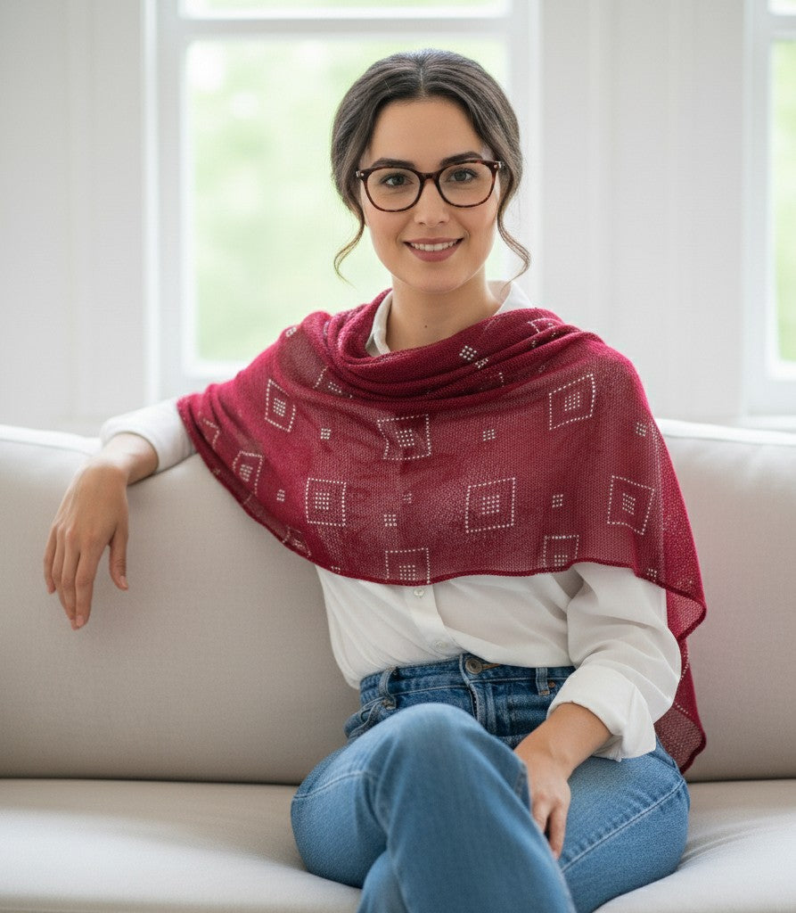 Woman wearing a red patterned scarf sitting on a couch.