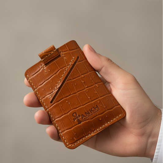 Hand holding a brown leather cardholder with 'Quiksilver' branding against a neutral background