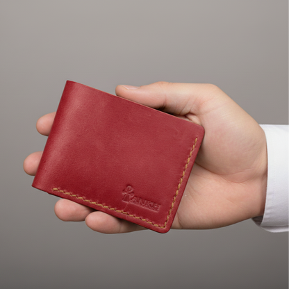 Hand holding a red leather wallet against a gray background