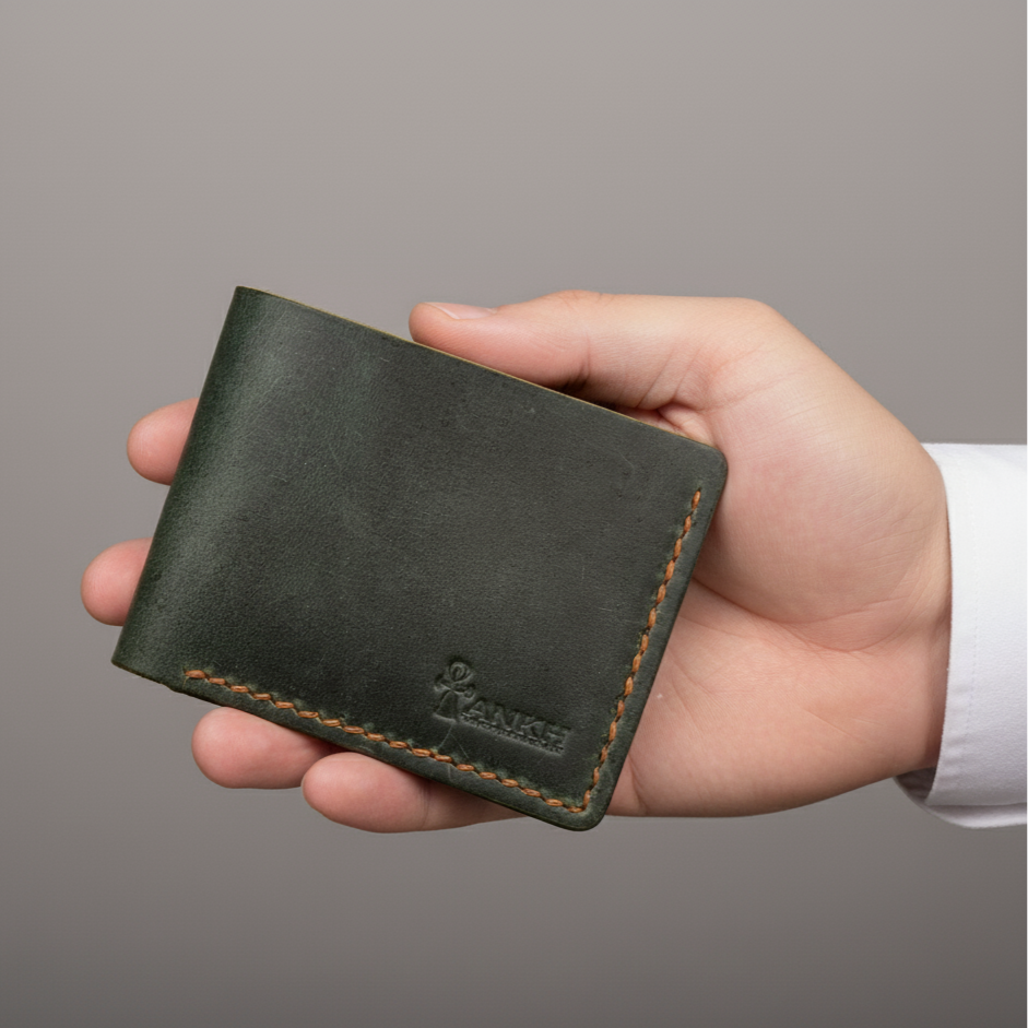 Hand holding a green leather wallet against a gray background