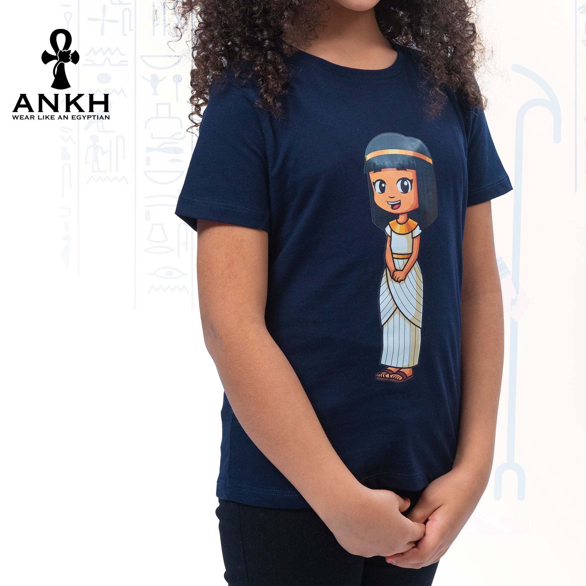 A child wearing Ankh’s navy blue t-shirt adorned with ‘Anippe’, a cartoony Egyptian girl character printed on premium quality 100% Egyptian cotton - perfect attire reflecting ancient Egyptian culture