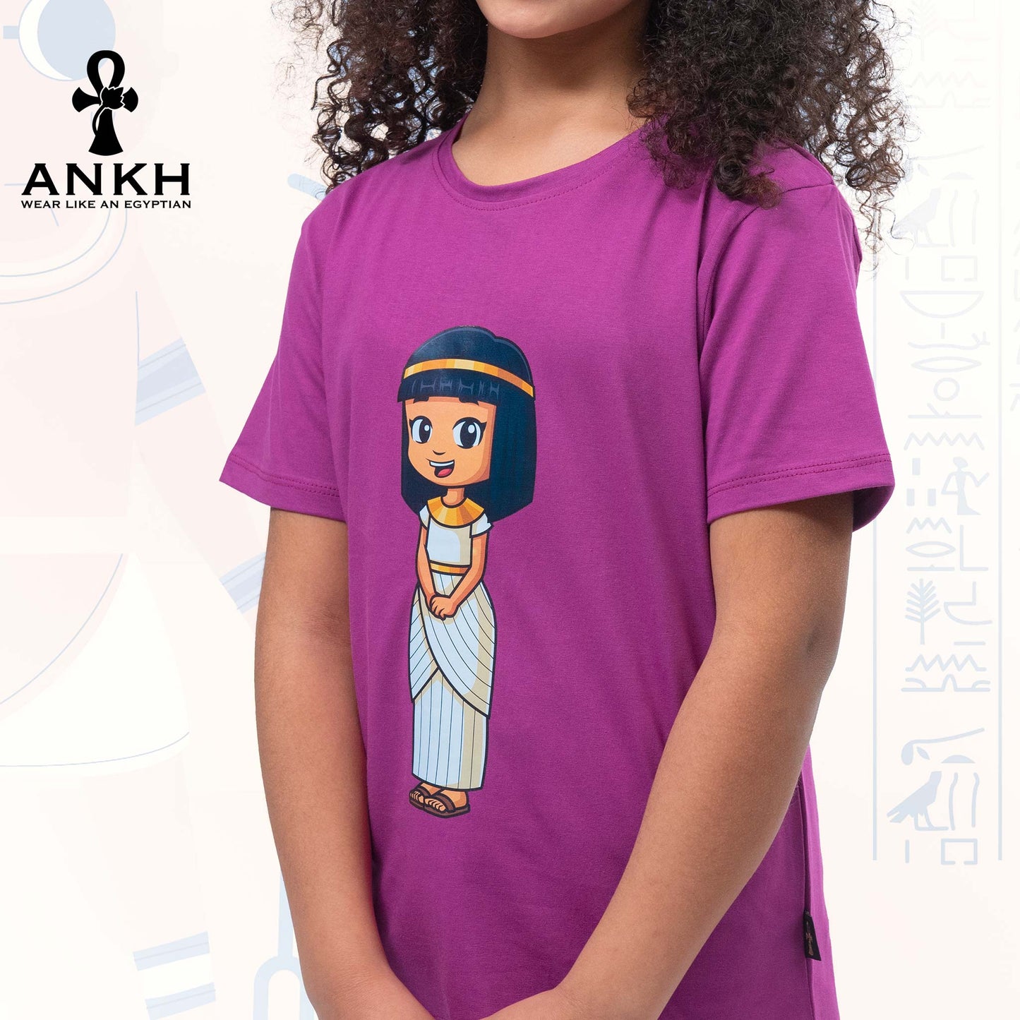 A child wearing Ankh’s pink-purple t-shirt adorned with ‘Anippe’, a cartoony Egyptian girl character printed on premium quality 100% Egyptian cotton - perfect attire reflecting ancient Egyptian culture